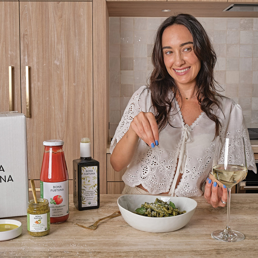 Woman enjoying a meal with a glass of wine in a kitchen setting - italian food subscription box