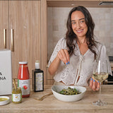 Woman enjoying a meal with a glass of wine in a kitchen setting - italian food subscription box