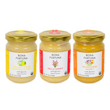 Three glass jars of Bona Furtuna organic honey arranged side by side on a white background. The jars have gold lids and labels for Sicilian Lemon Blossom Honey, Sulla Honey, and Wildflower Honey.