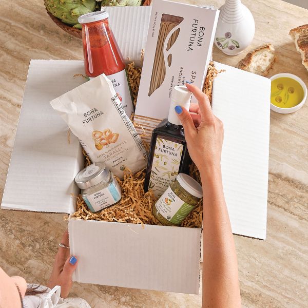 Person opening a box of Bona Furtuna products on a wooden table.