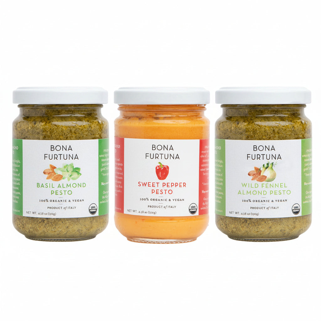 Three glass jars of Bona Furtuna pesto sauce on a white background: Basil Almond Pesto with green labeling, Sweet Pepper Pesto with a red-orange label, and Wild Fennel Almond Pesto with green labeling.